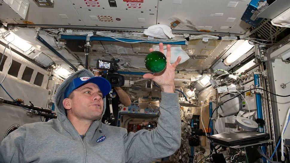 Астронавт NASA и экспедиции 68 Джош Кассада (Josh A. Cassada) играет с водой в сфере, окрашенной зелёным пищевым красителем,